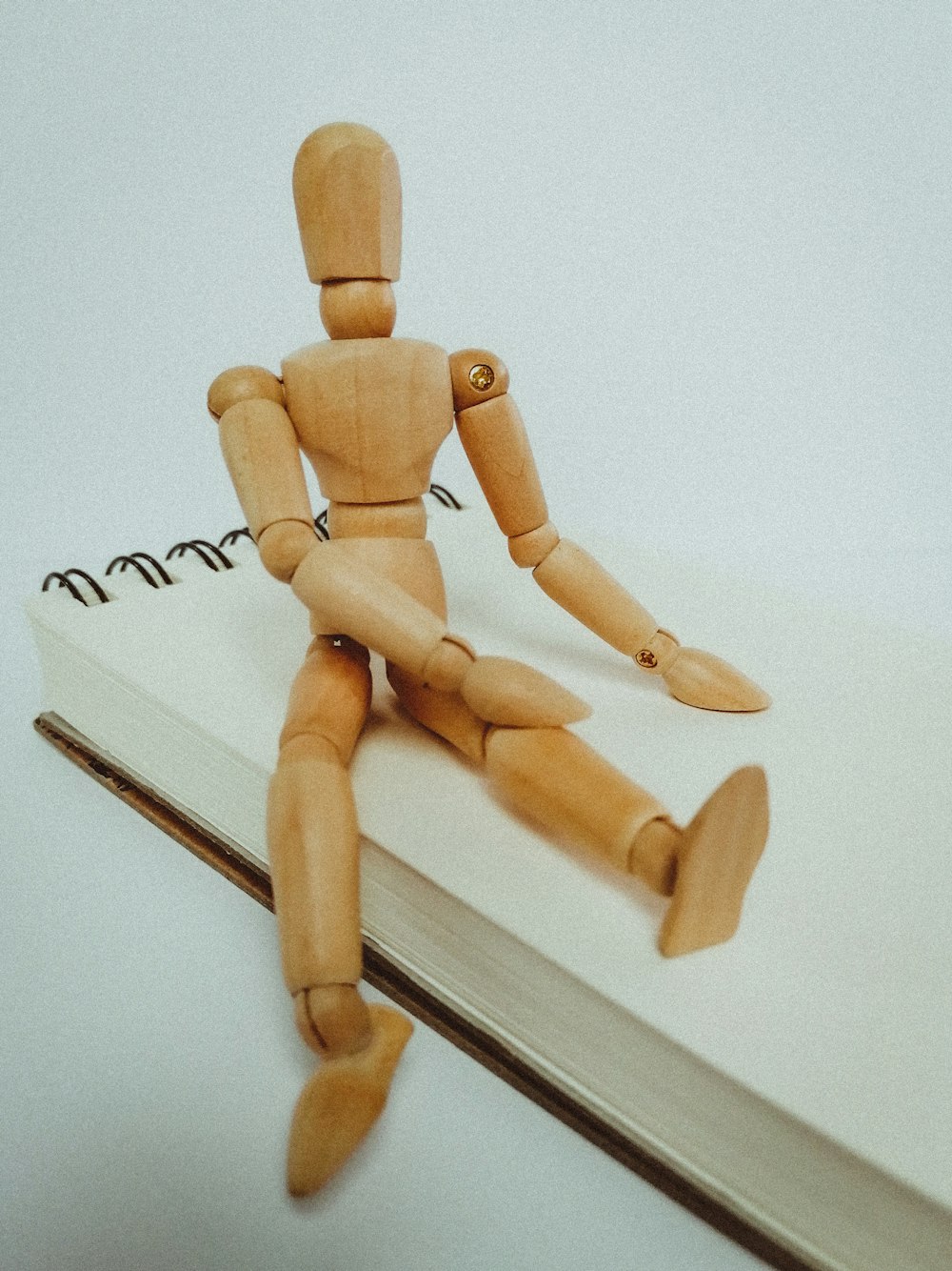 figura humana de madeira marrom na mesa branca