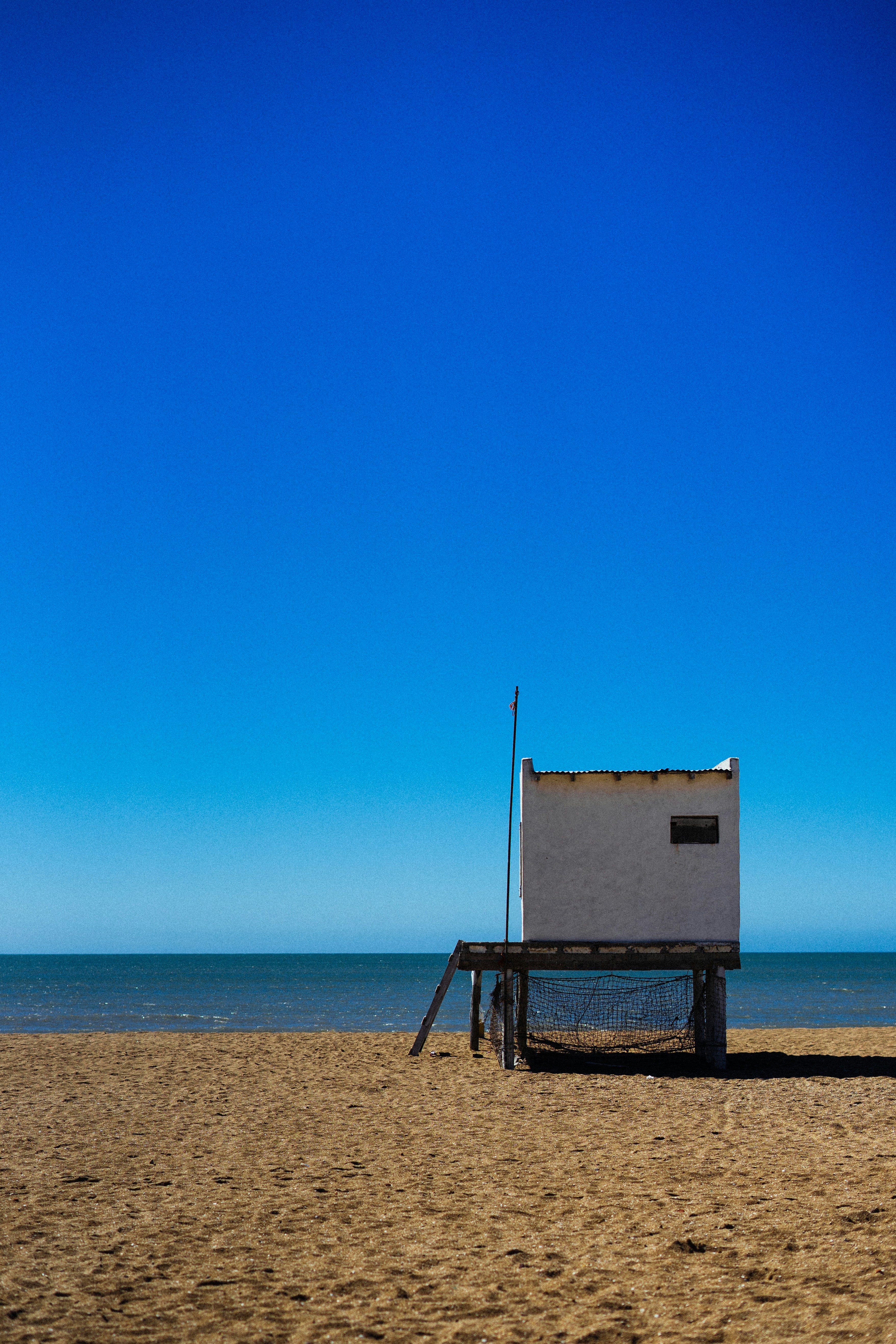 white wooden lifeguard house on beach shore during daytime