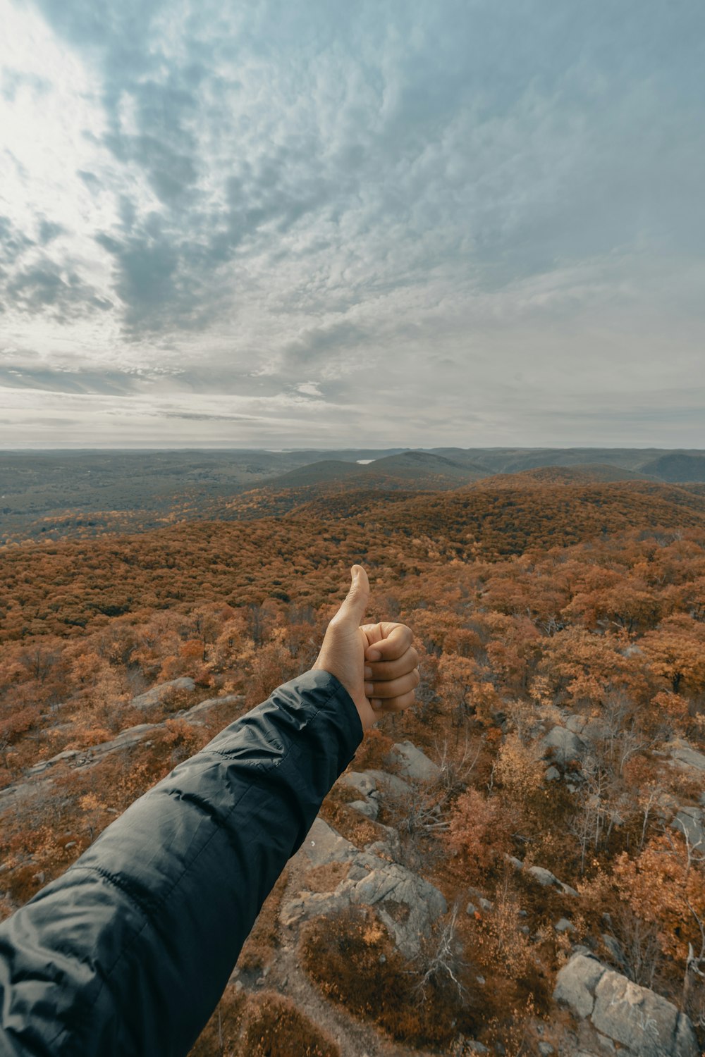 Person in grauen Hosen auf braunem und grünem Rasen unter weißen Wolken tagsüber