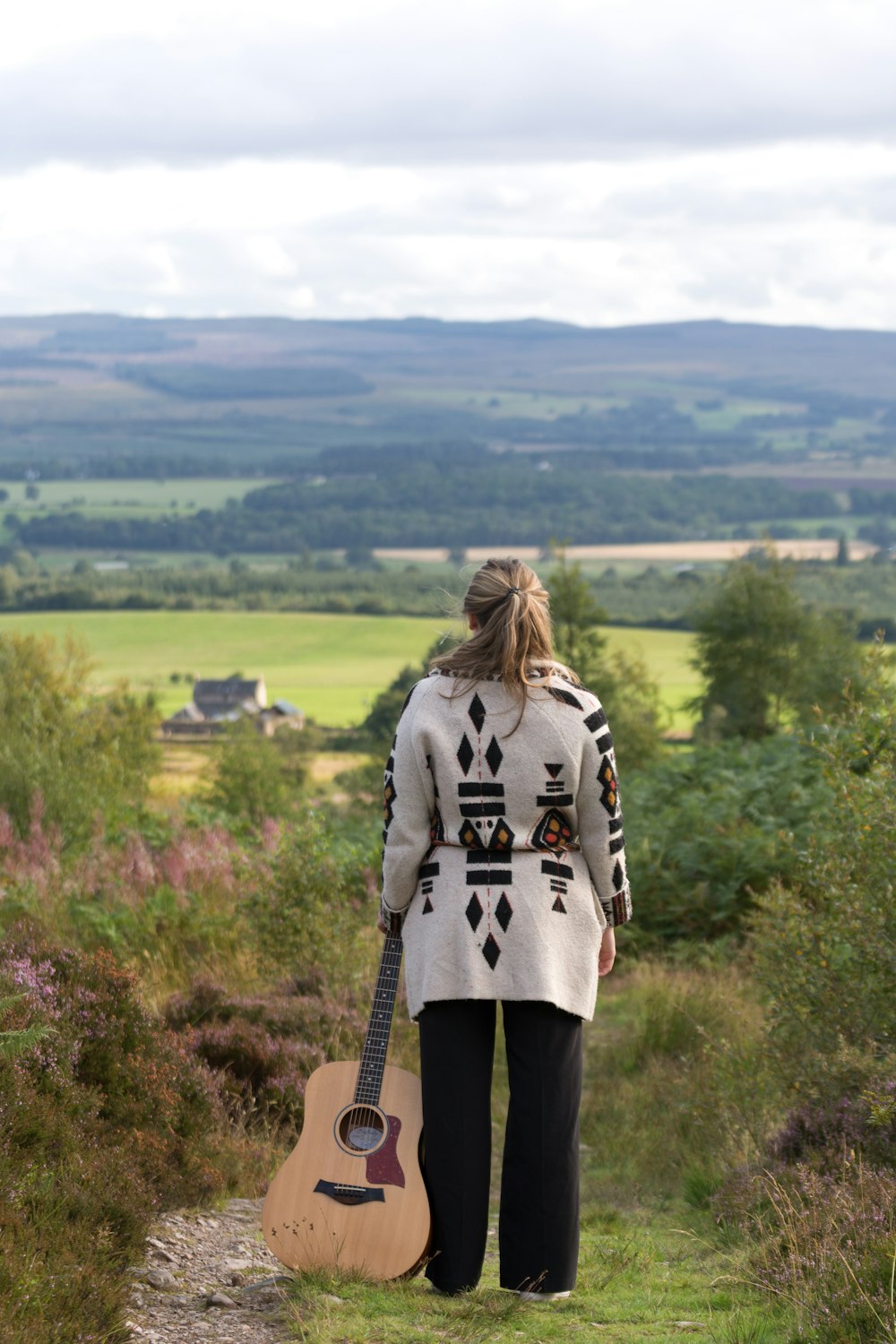 woman in gray coat standing on brown rock during daytime