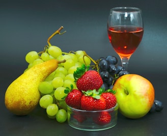 A colorful still life painting showing a bowl of fresh fruit on a rustic table.