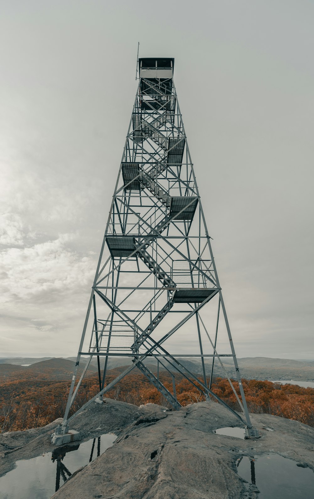 Schwarzer Metallturm auf braunem Feld unter weißen Wolken