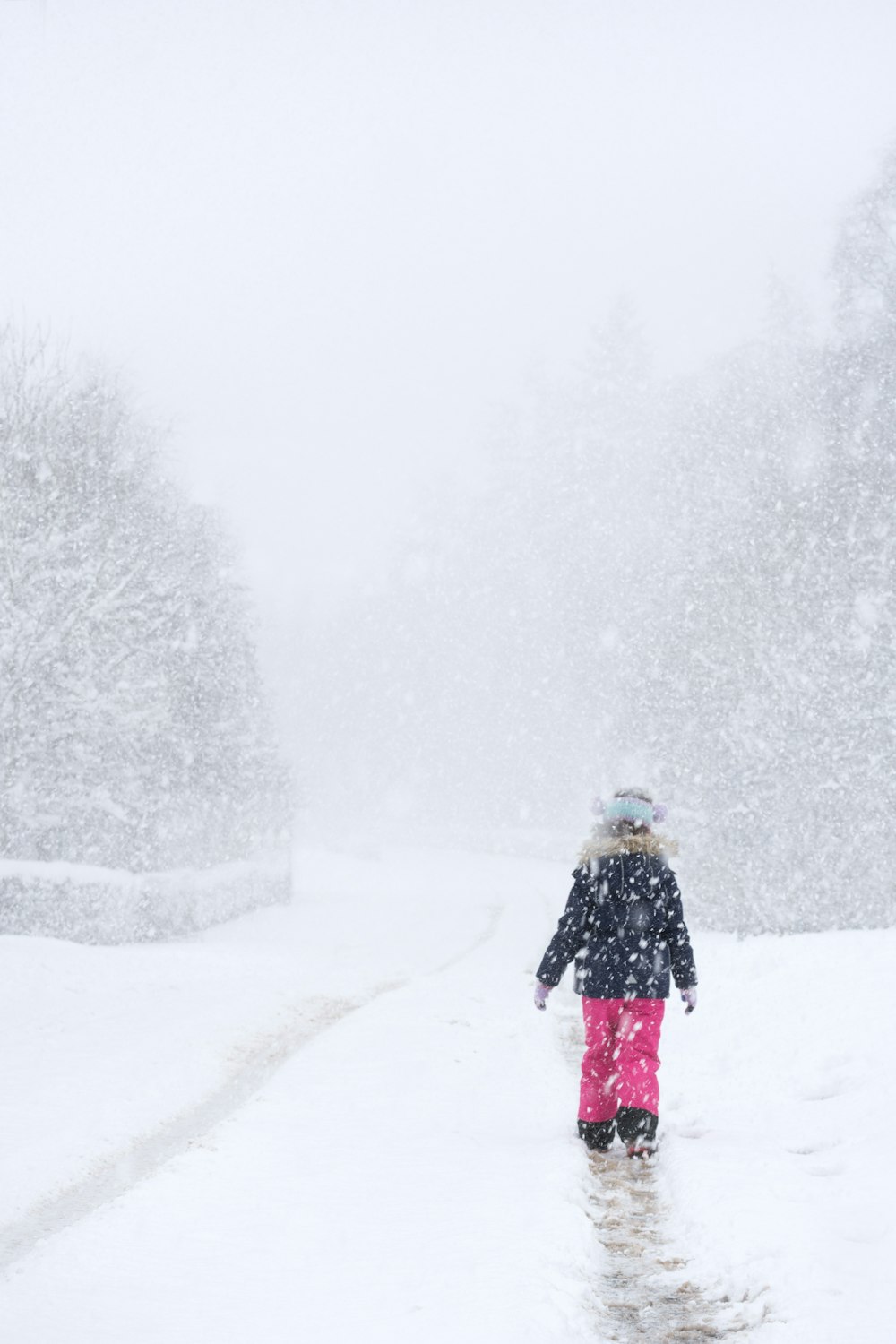 Person in schwarzer Jacke, die tagsüber auf schneebedecktem Boden läuft