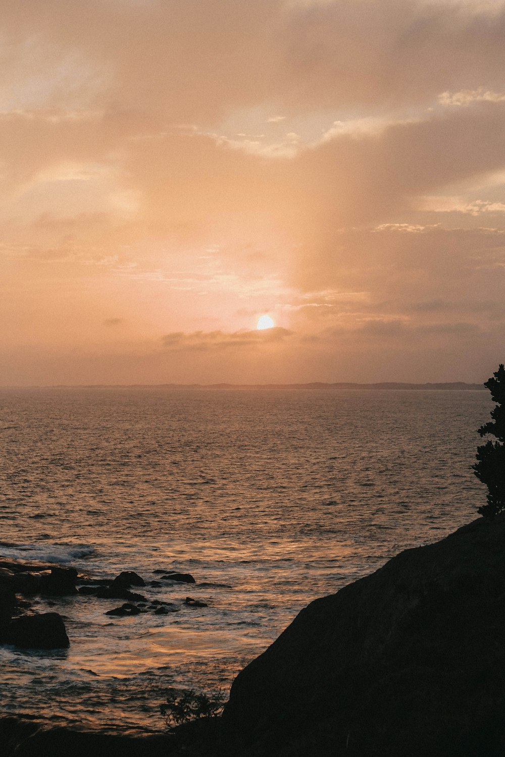 silhouette of rocks on sea during sunset