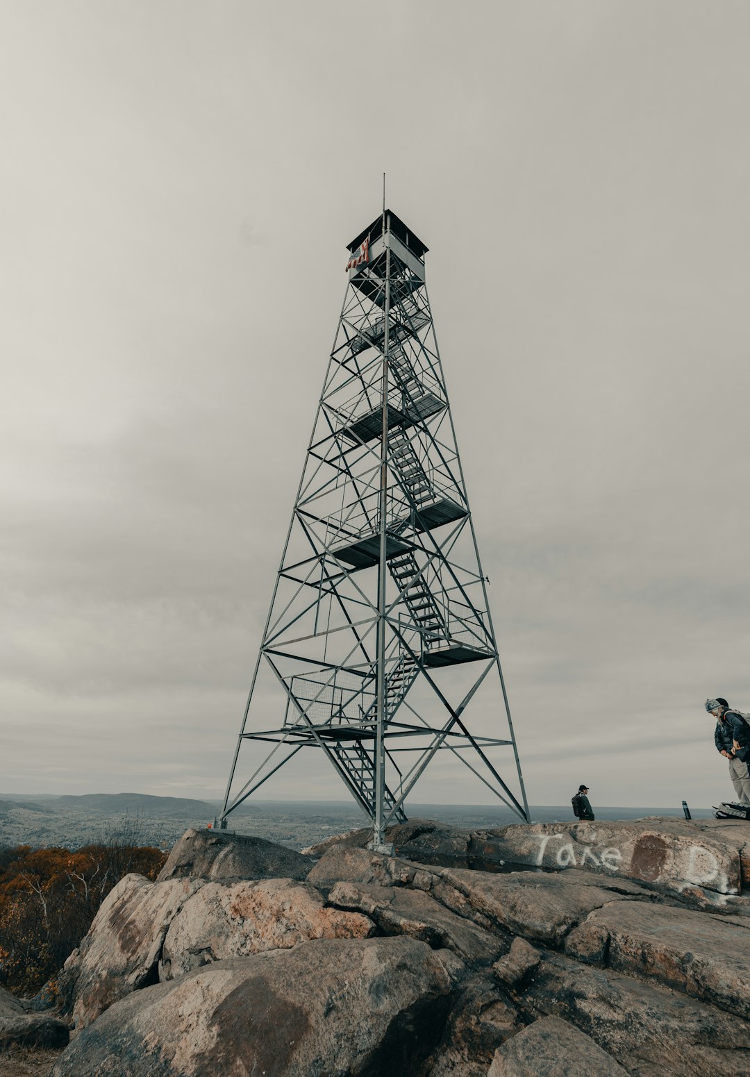 people standing on rock near tower during daytime