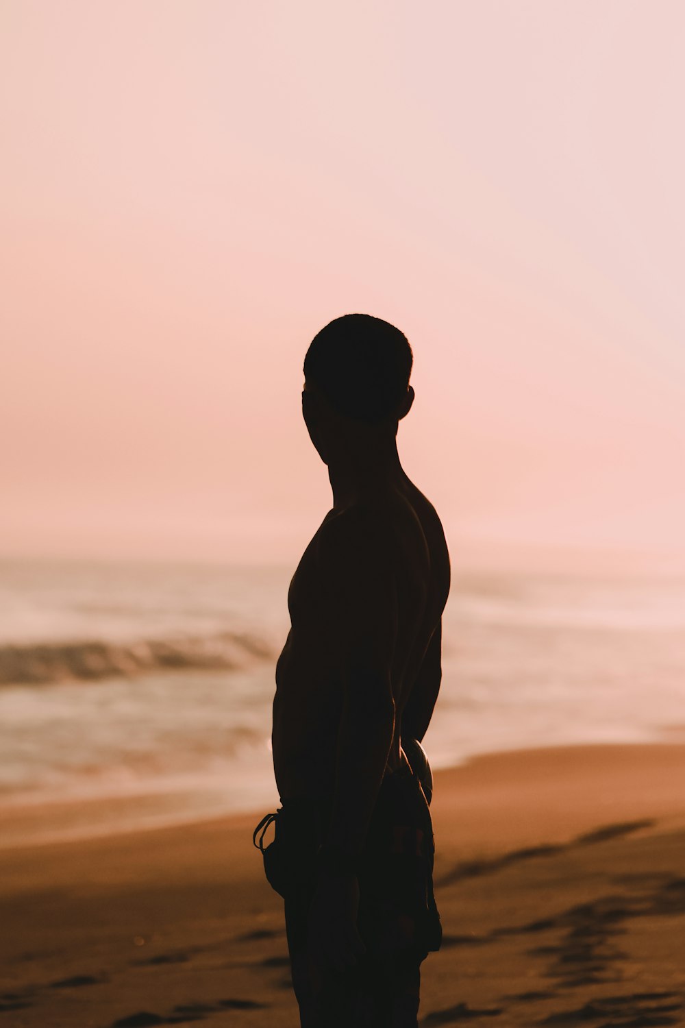 silhouette of man standing on beach during sunset