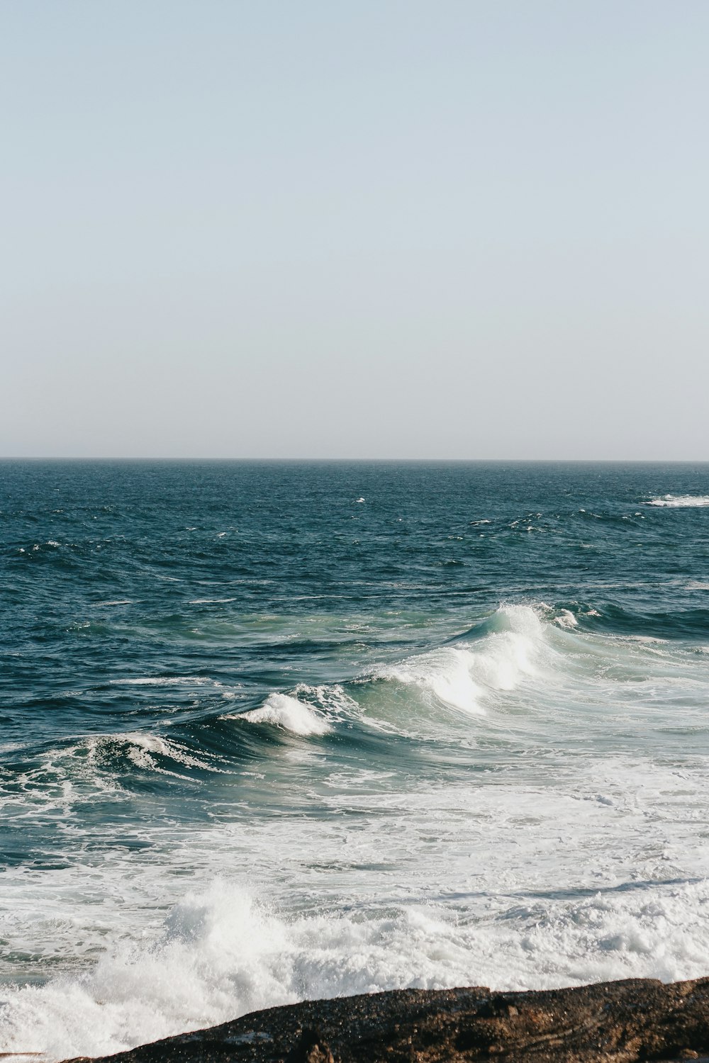 ocean waves under white sky during daytime