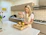 A smiling woman easily cleaning the electric vegetable slicer under running water.
