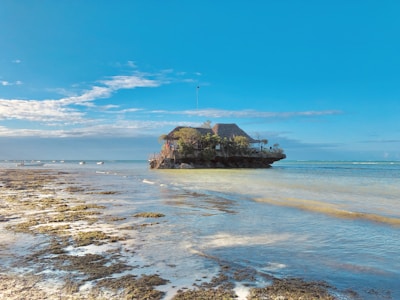 brown rock formation on sea under blue sky during daytime