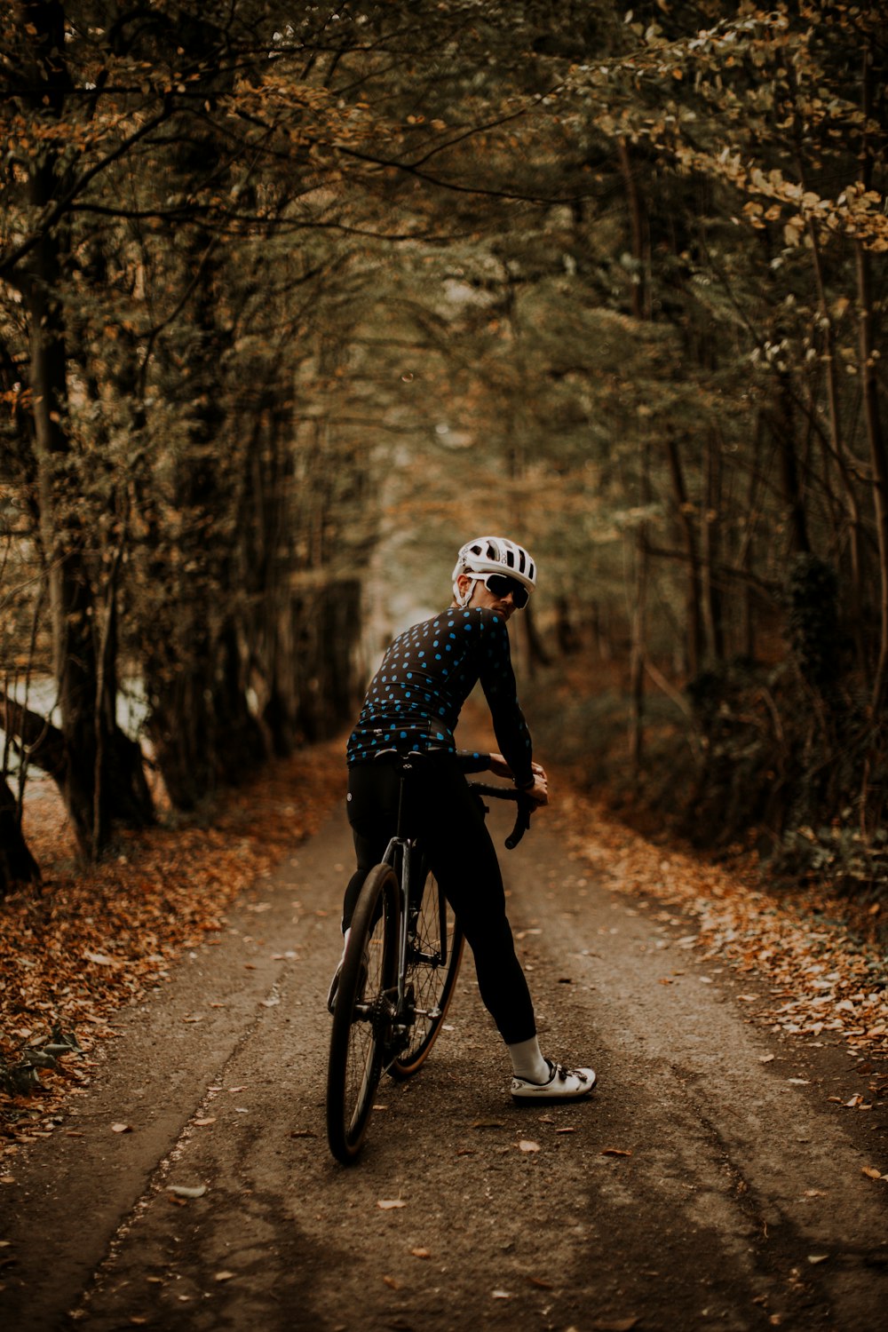 man in black and white shirt riding bicycle on road during daytime