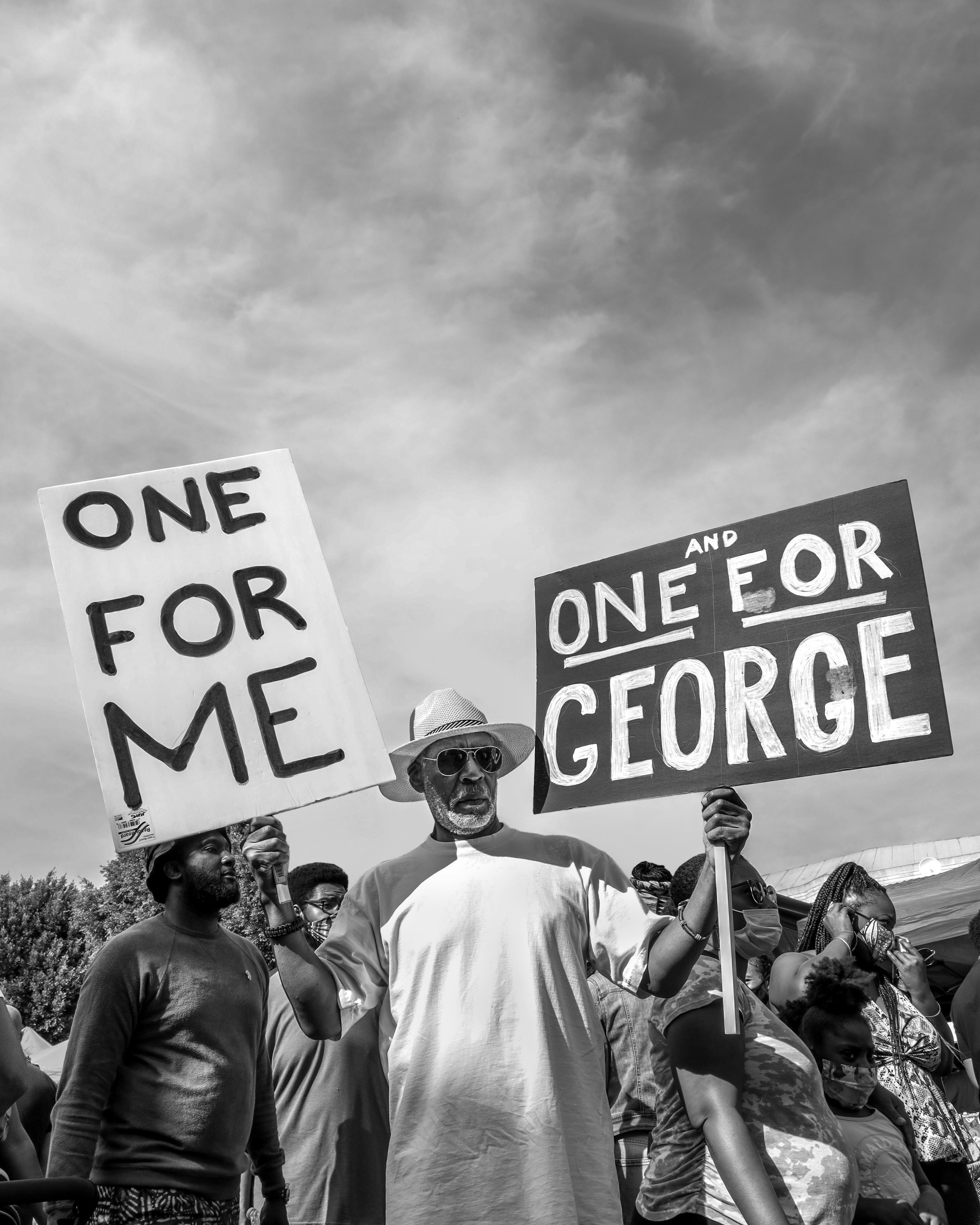 grayscale photo of people standing near the road sign