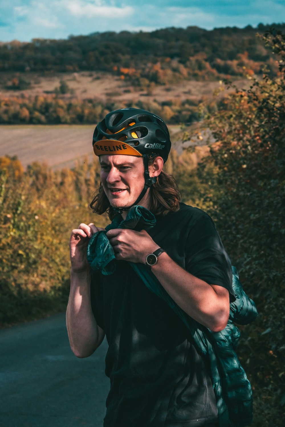 man in black crew neck t-shirt and black helmet holding green leaf plant during daytime