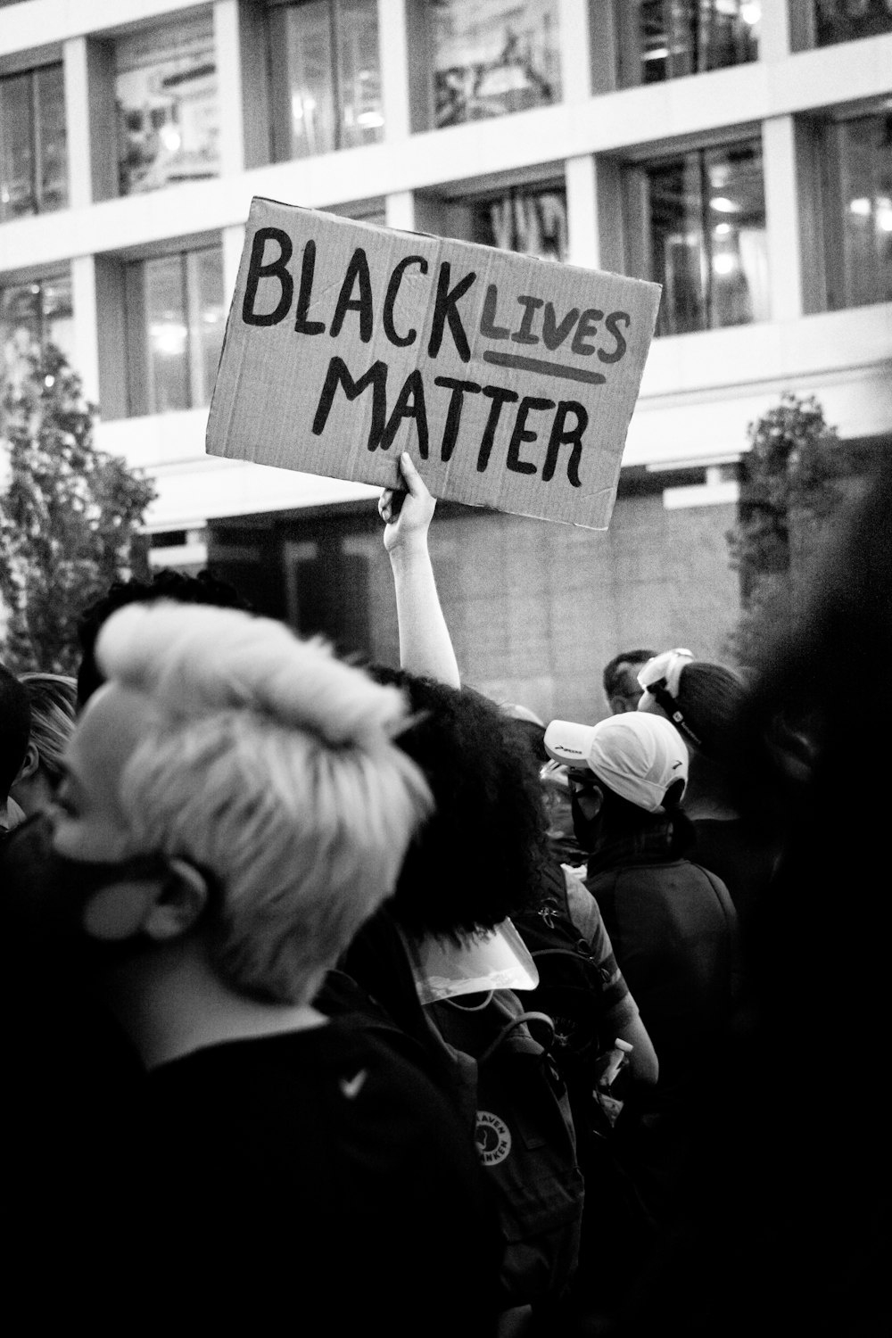 grayscale photo of people holding white and black board