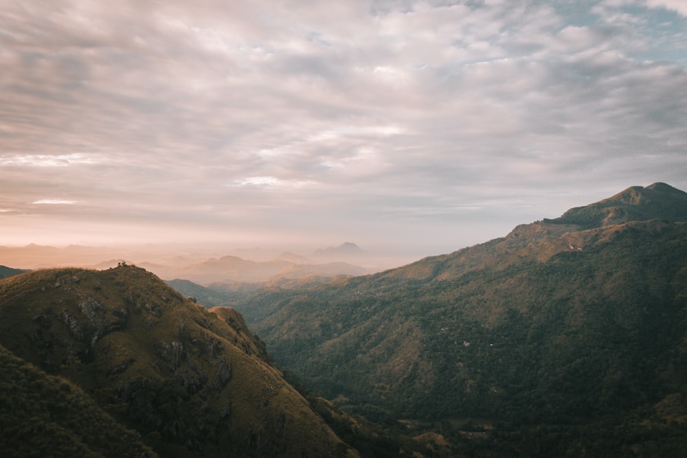 montagnes vertes et brunes sous des nuages blancs pendant la journée