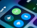 Close-up of a smartphone screen displaying various connectivity icons, including a green Wi-Fi symbol, a blue Bluetooth icon, and an airplane mode icon. The image focuses on the section of the control center, highlighting these options with a blurred background.