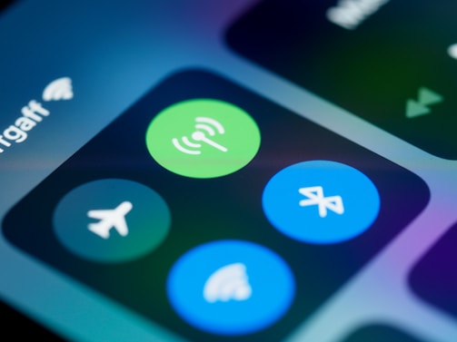 Close-up of a smartphone screen displaying various connectivity icons, including a green Wi-Fi symbol, a blue Bluetooth icon, and an airplane mode icon. The image focuses on the section of the control center, highlighting these options with a blurred background.