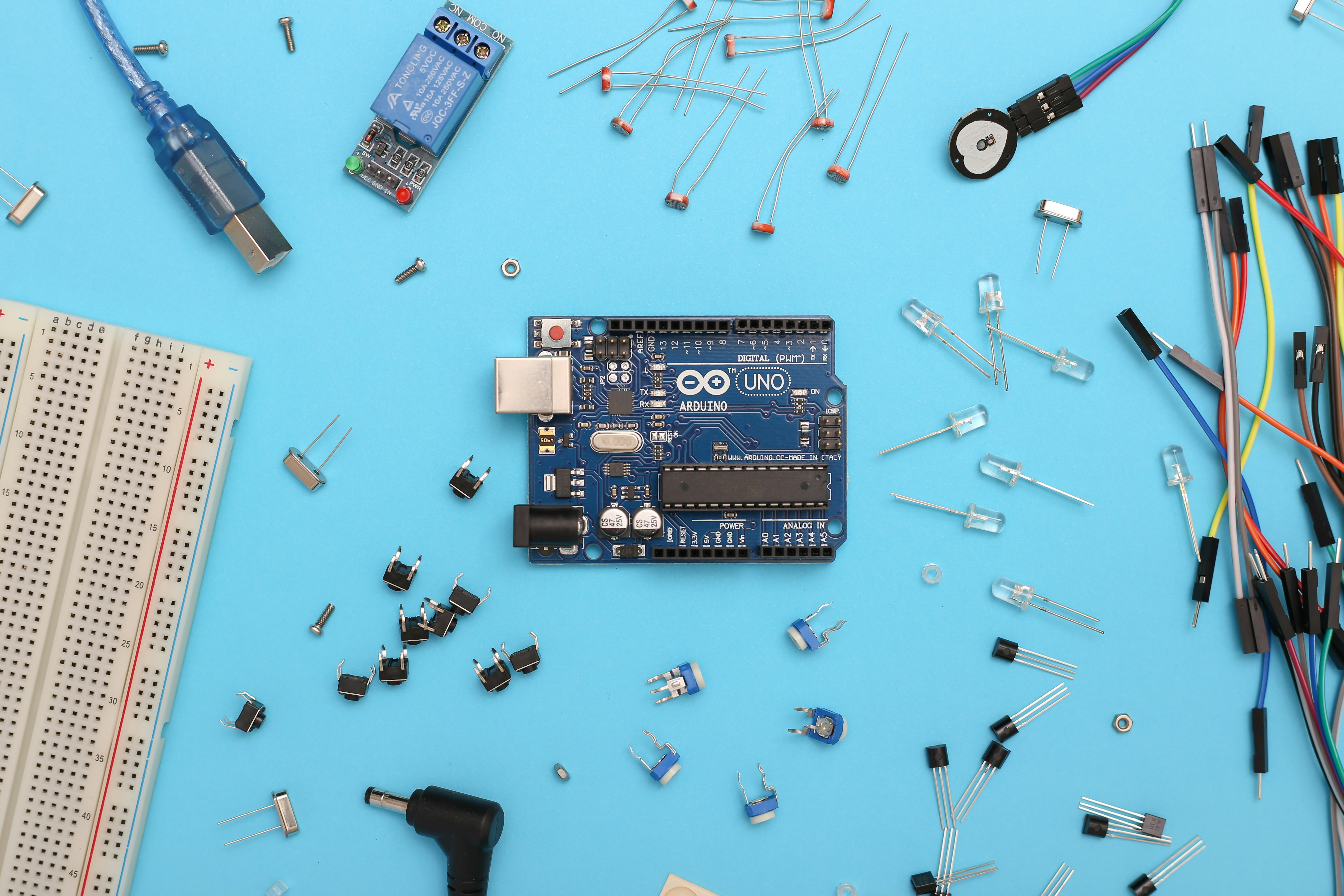 Arduino Uno and electronic parts on a blue surface.