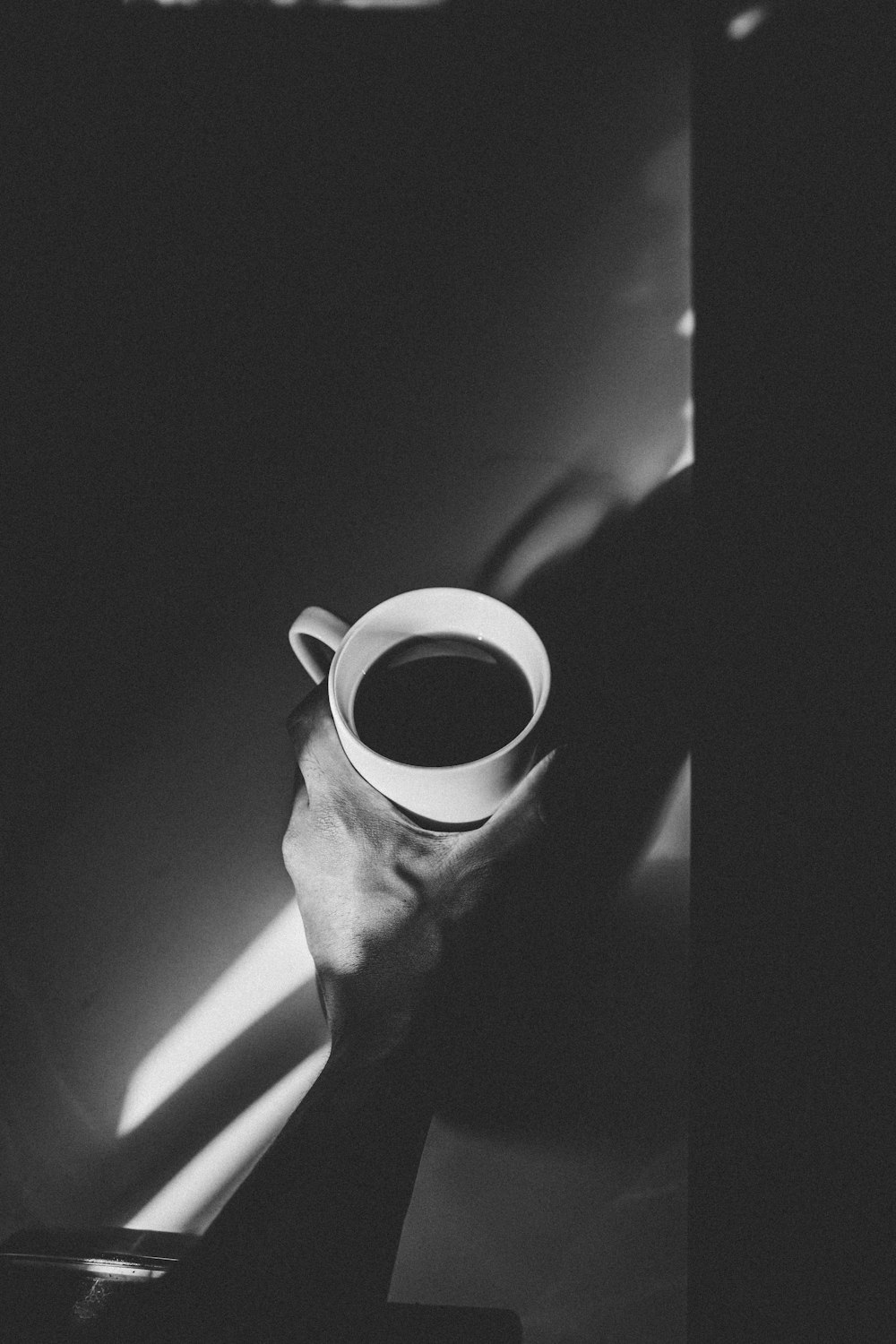 grayscale photo of person holding ceramic mug