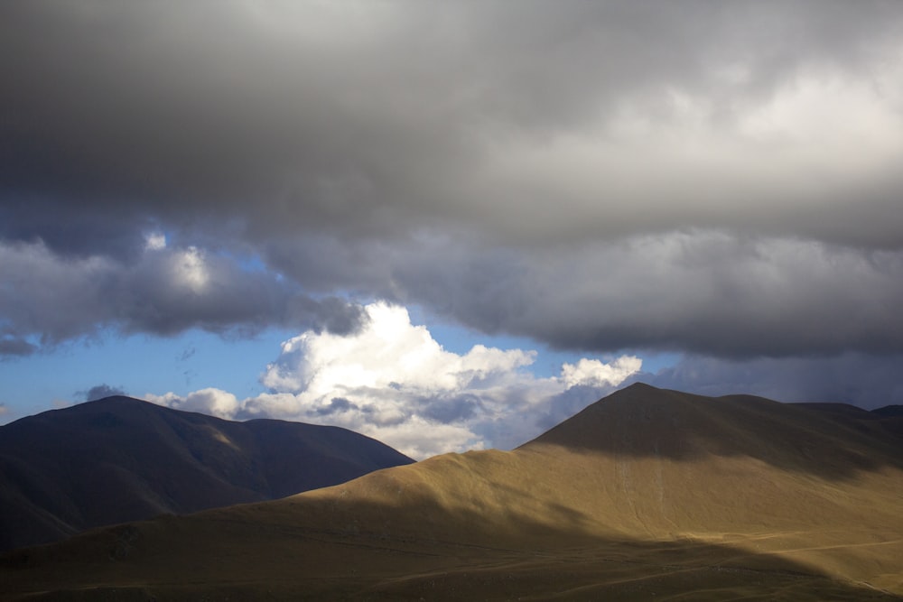 brown mountain under white clouds during daytime