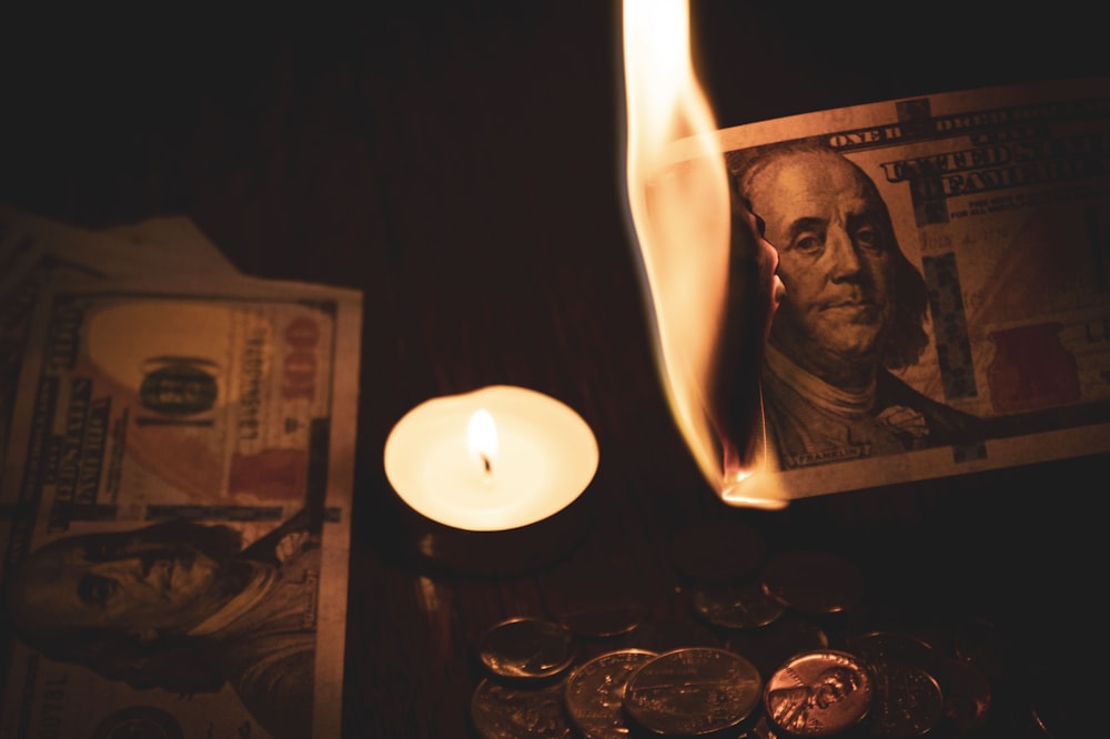 white pillar candle beside 100 us dollar bill