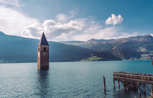 The iconic submerged bell tower rising from the lake under a bright blue sky.