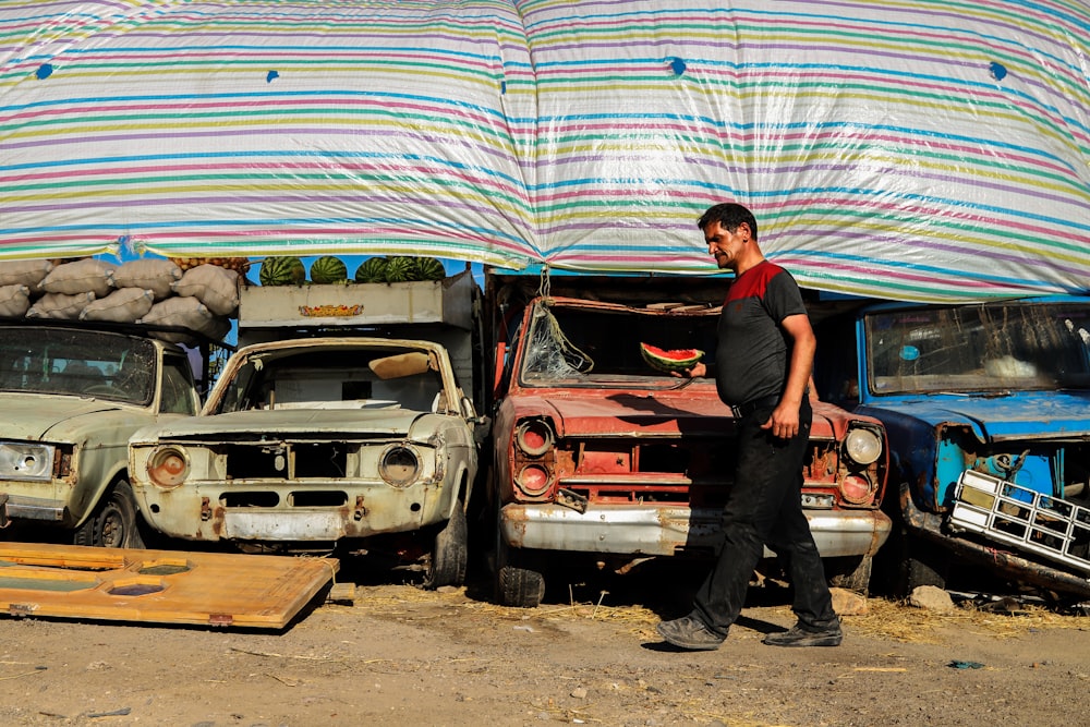 man in black t-shirt standing beside red car during daytime