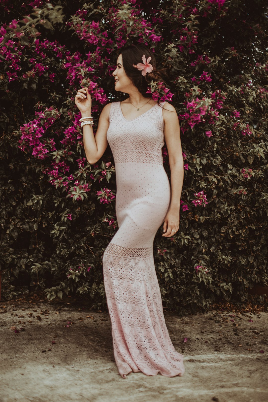 woman in white floral dress standing beside pink flowers