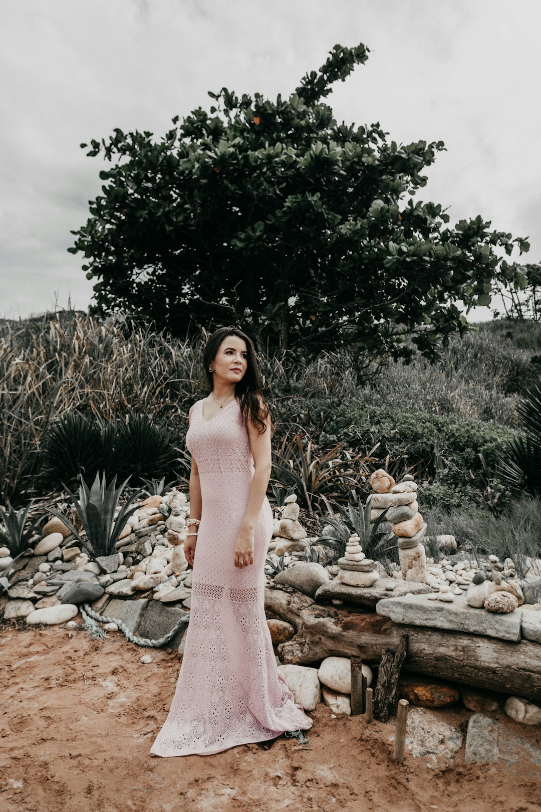 woman in pink dress standing near green tree during daytime