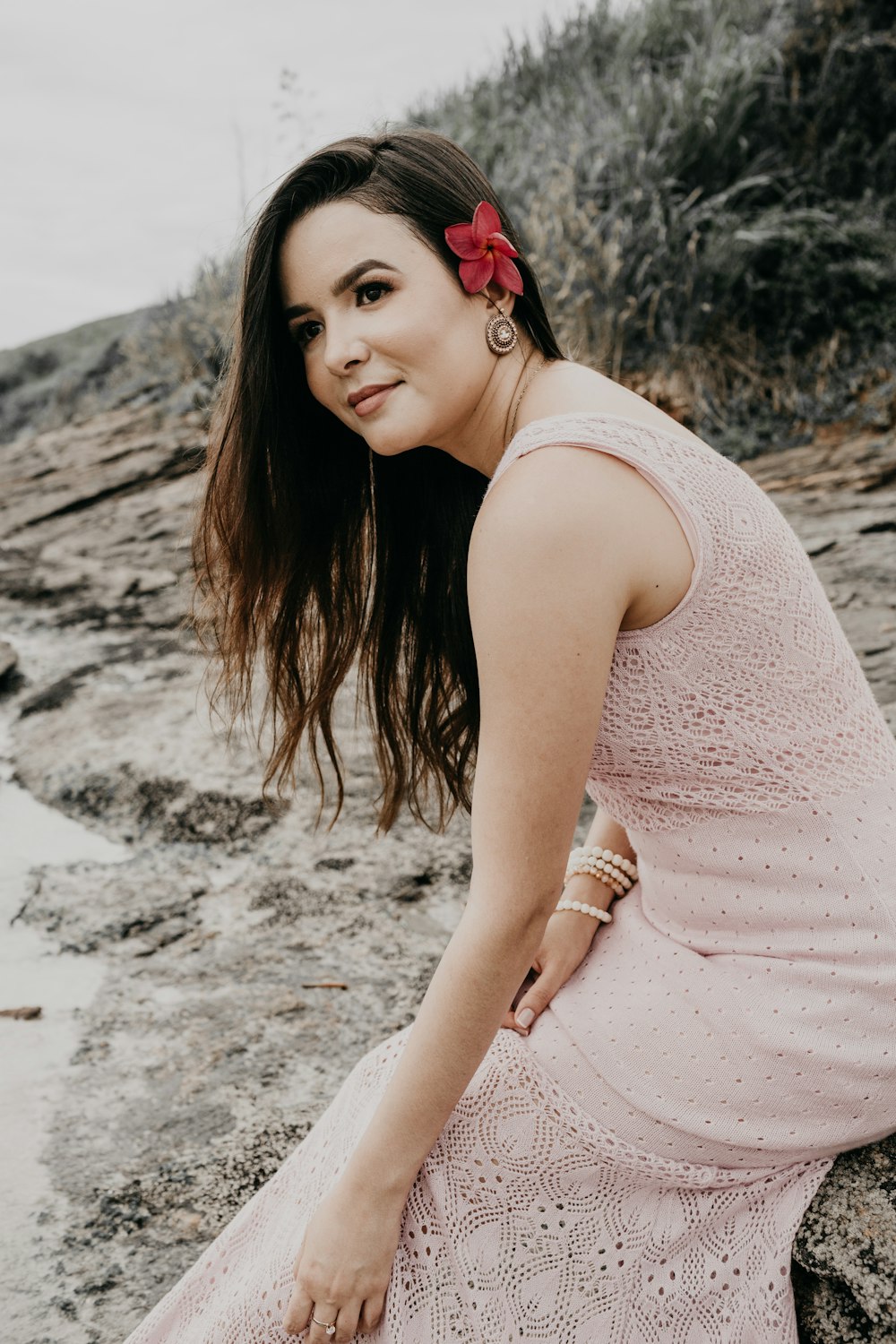 woman in pink sleeveless dress sitting on white sand during daytime