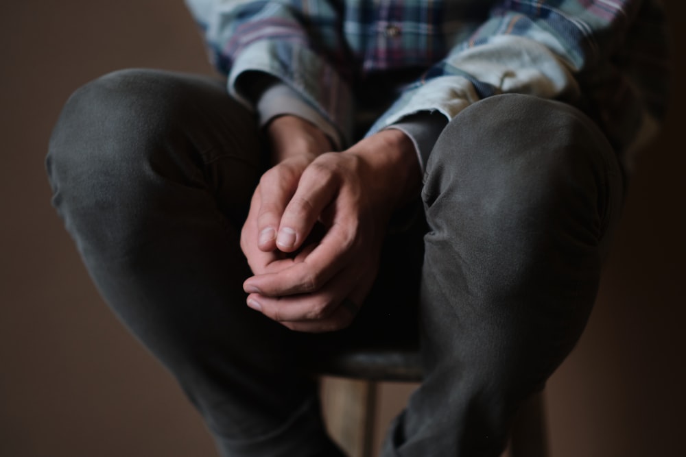 person in black pants sitting on brown wooden chair