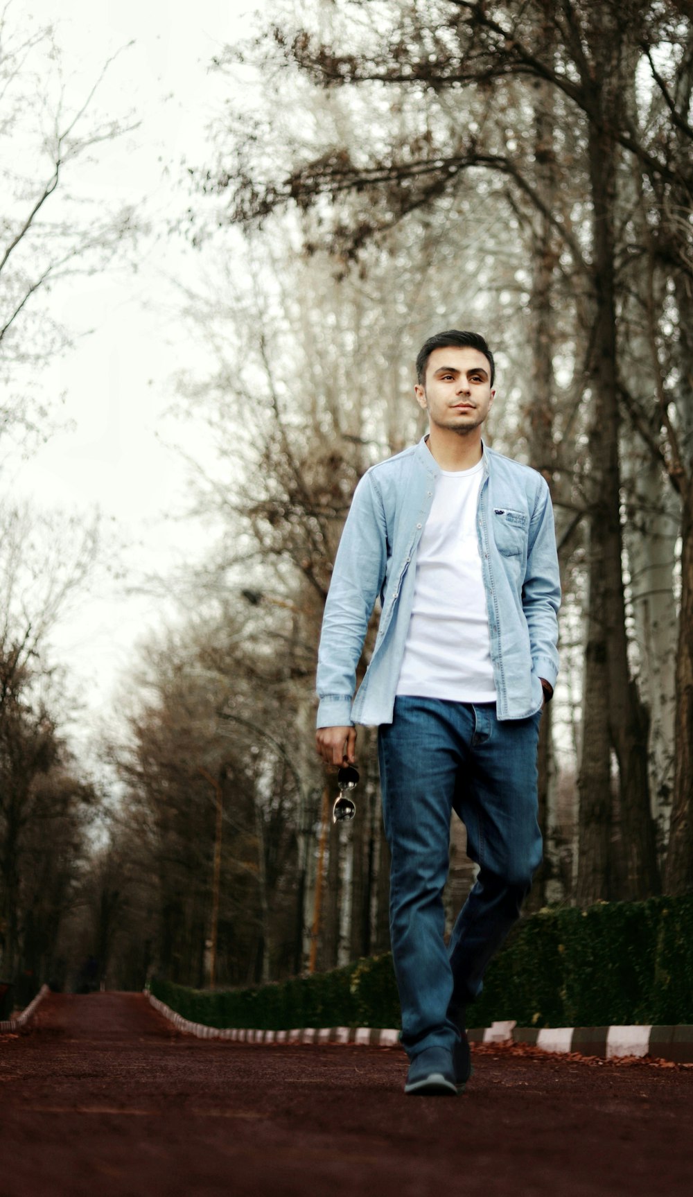 man in white dress shirt and blue denim jeans standing on green grass field during daytime