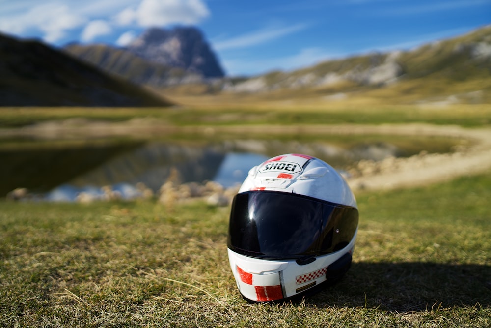 capacete branco e vermelho no campo de grama verde durante o dia