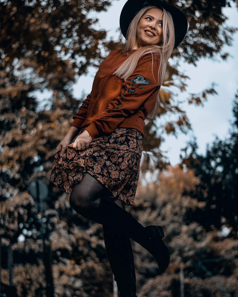 woman in brown long sleeve shirt and black pants standing under blue sky during daytime