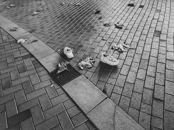 Black and white photograph capturing a quiet, abandoned urban corner with peeling paint and scattered leaves.