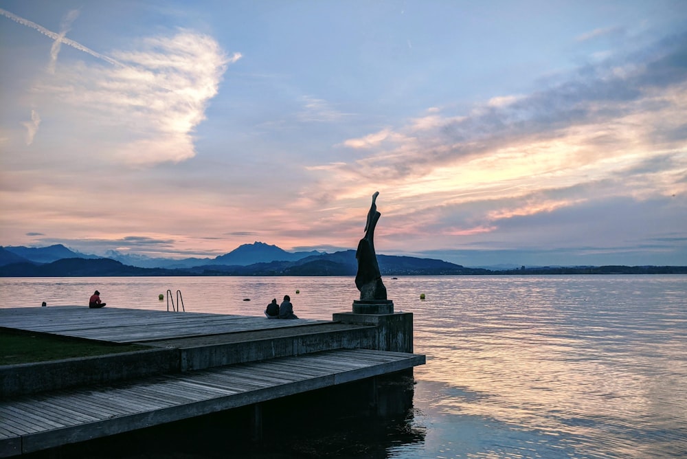 person sitting on wooden dock during daytime