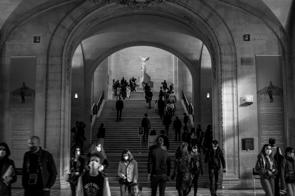 people walking inside building in grayscale photography