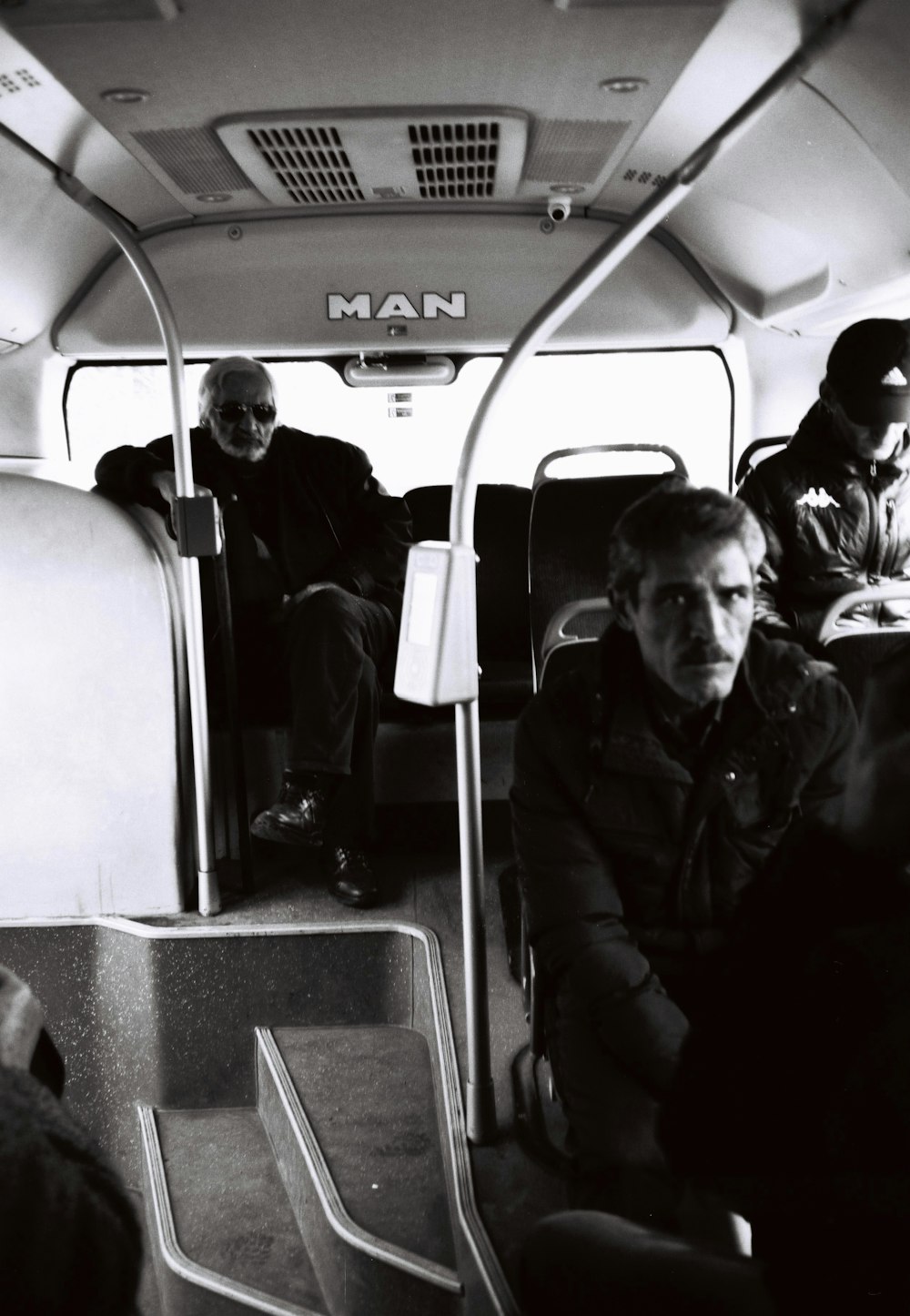 grayscale photo of man in jacket sitting on car seat