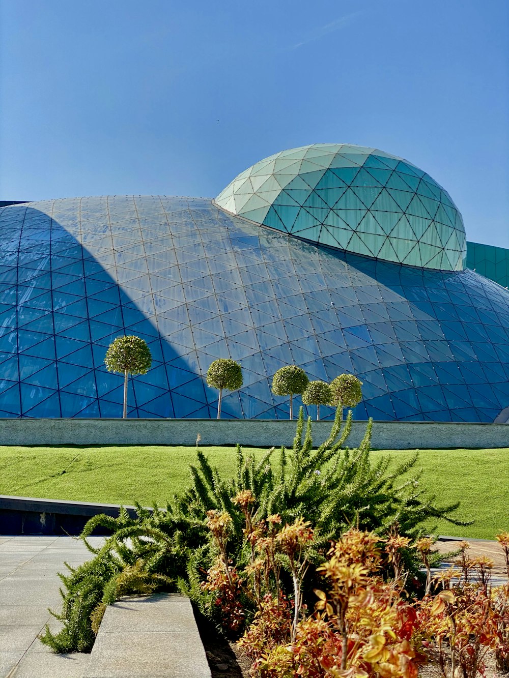 Bâtiment en forme de dôme de verre bleu près du champ d’herbe verte pendant la journée