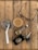 An assortment of everyday items is arranged on a wooden surface. There is a glass of iced coffee with a straw, a pair of eyeglasses, a wristwatch with a gold and silver strap, a key fob with several keys, and a leather wallet with a badge on it.