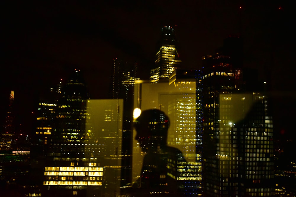 silhouette dell'uomo in piedi vicino a grattacieli durante la notte