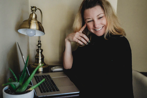 woman in black sleeveless shirt sitting beside table with macbook pro
