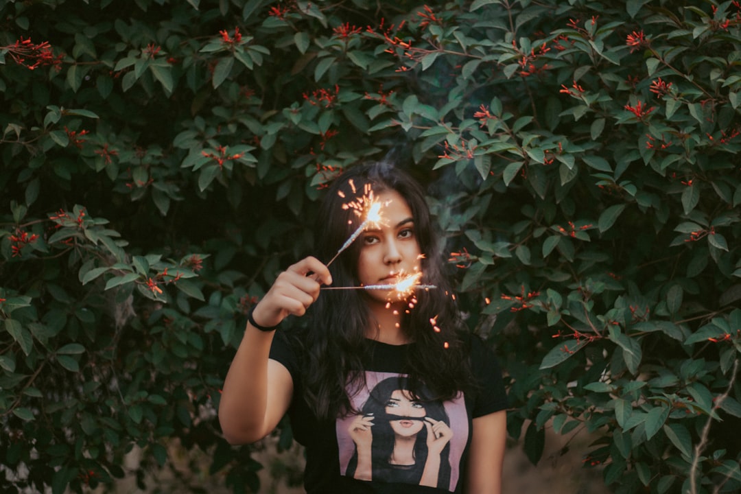 woman in white and black t-shirt standing beside green leaves