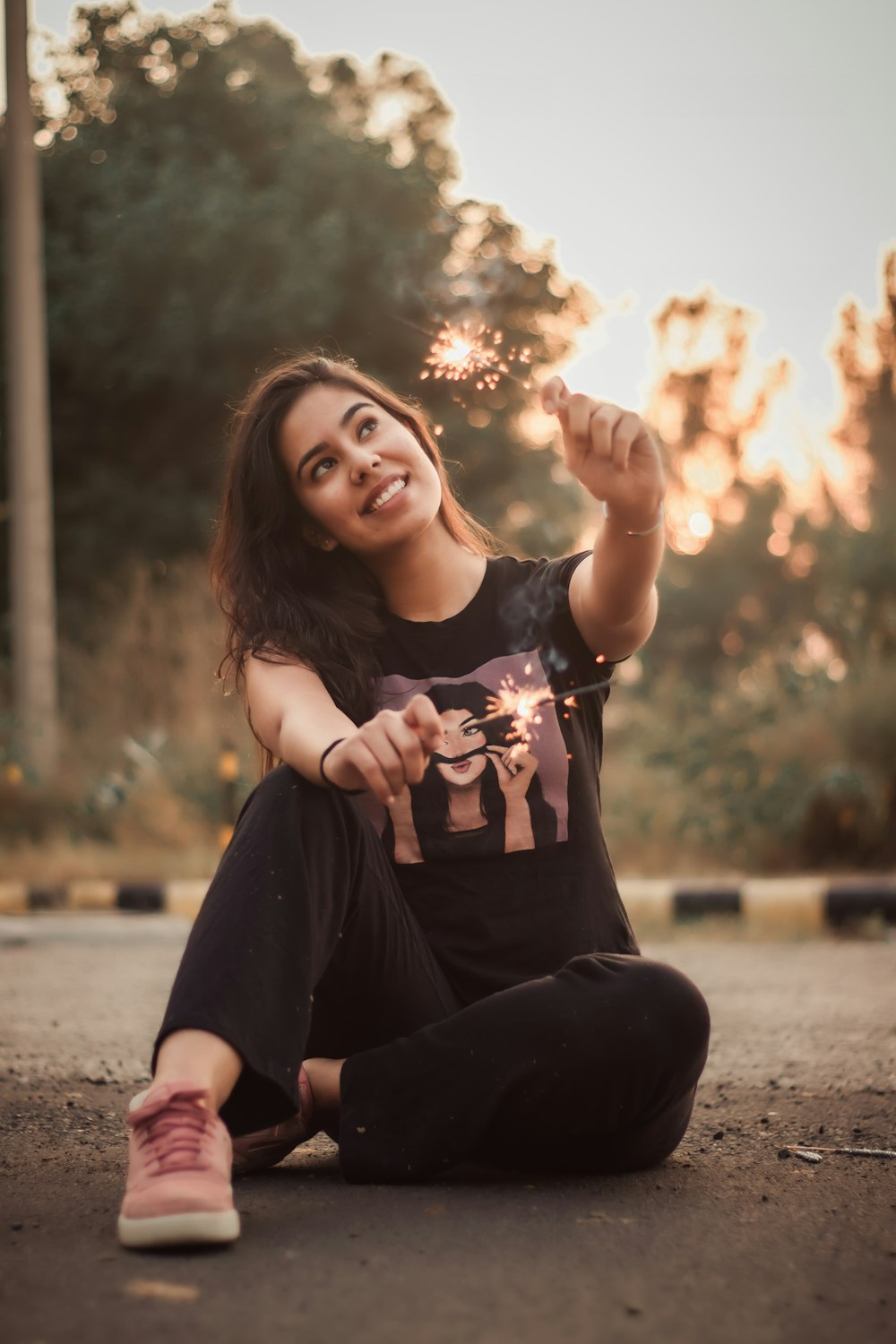 woman in black tank top and black pants sitting on gray concrete pavement during daytime