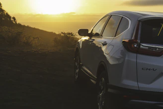 Sunset view of an Innova Crysta parked at a rest area with a backdrop of rolling hills.