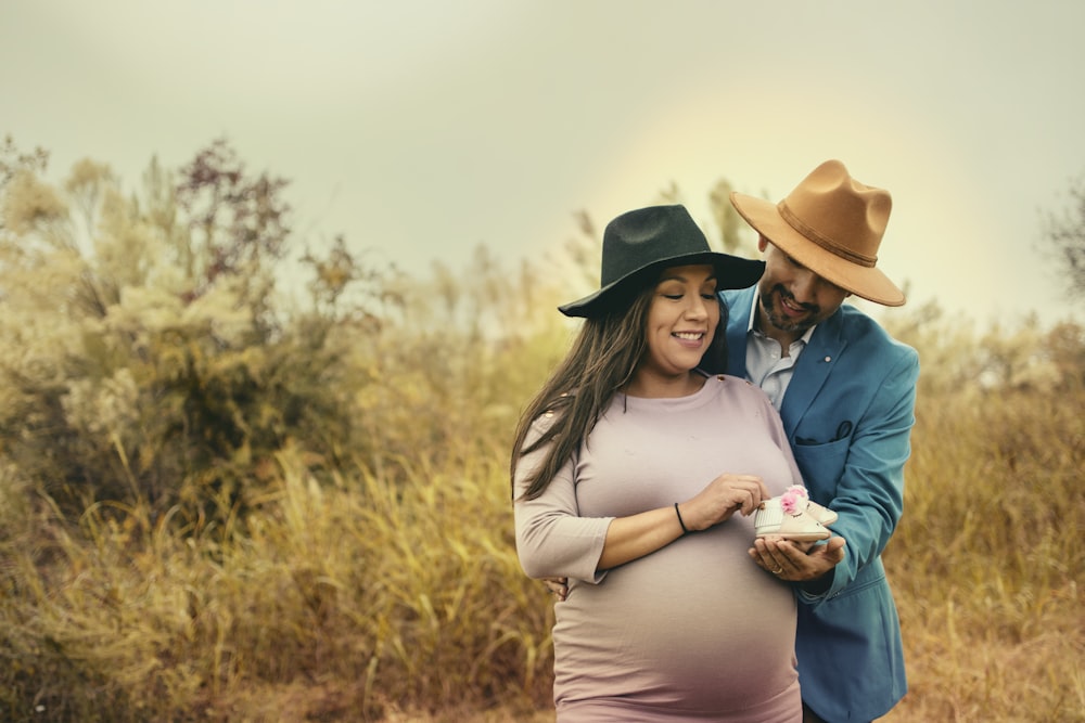 woman in white long sleeve shirt and brown cowboy hat holding baby in blue jacket during