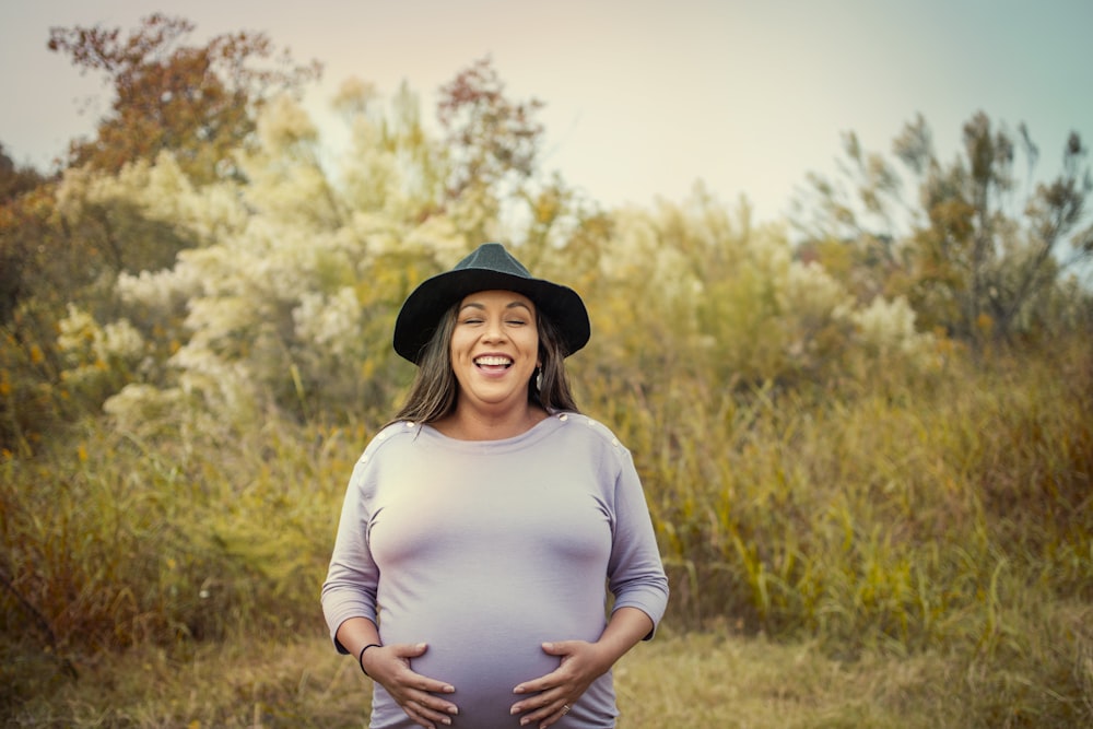 woman in white long sleeve shirt and black hat standing on brown grass field during daytime