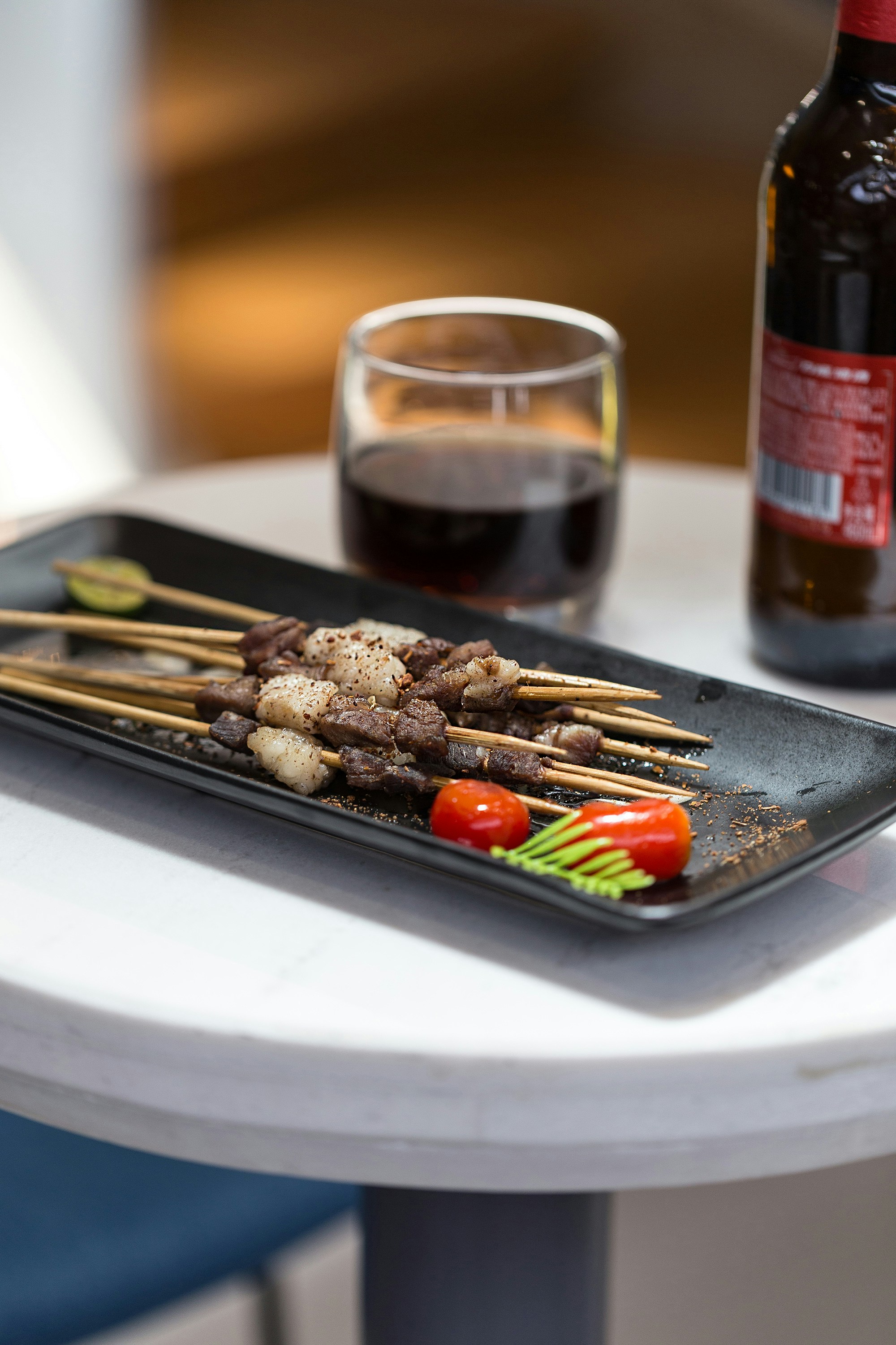 grilled meat on white ceramic plate beside clear drinking glass