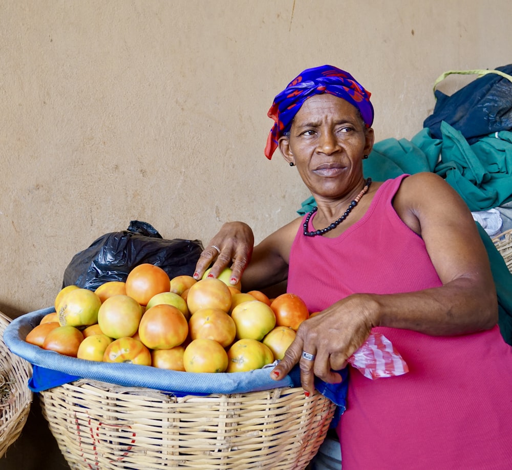 woman in pink tank top sitting beside yellow round fruits