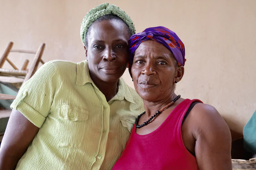 A mother and her adult daughter resting cheek to cheek, smiling warmly together.
