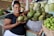 Smiling woman holding a basket of fresh fruits inside a bright supermarket aisle.